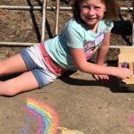 girl drawing outside with chalk her idea of the universe.