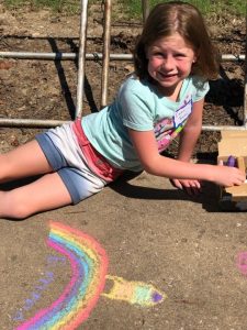 girl drawing outside with chalk her idea of the universe.